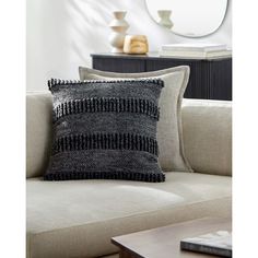 a black and white pillow sitting on top of a couch next to a wooden table