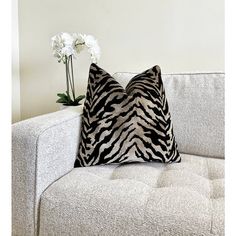 a zebra print pillow sitting on top of a couch next to a vase with flowers