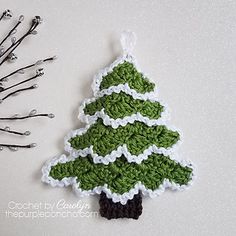 a crocheted christmas tree ornament next to some knitting pins and needles