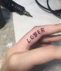 a person's left hand with the word lover tattooed on it, in black ink