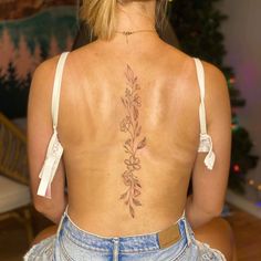 the back of a woman's body with flowers tattooed on her upper and lower back