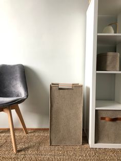 a room with a chair, bookshelf and storage bins