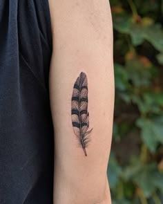 a black and white feather tattoo on the arm