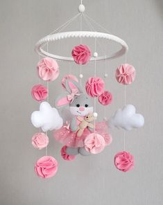 a baby mobile with pink flowers and a bunny in a tutu skirt hanging from the ceiling