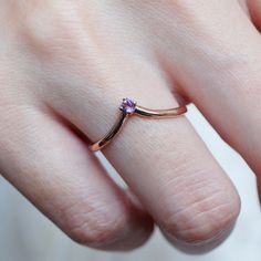 a woman's hand with a ring on it that has a purple stone in the middle