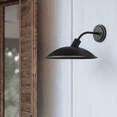 a black wall light hanging from the side of a white door with a mirror behind it