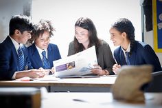 there are three people that are sitting at a table and one is looking at a book