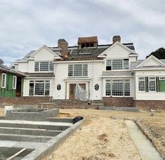 a large white house with green shutters on the front and side windows that are missing