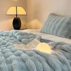 a bed with a book on it and a lamp in the corner next to it