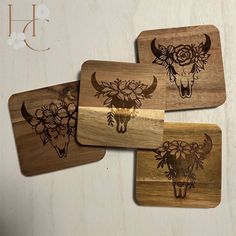 three wooden coasters with flowers and steer heads on them