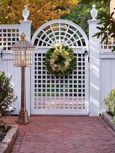 a white gate with a wreath on it and a lamp post in the foreground