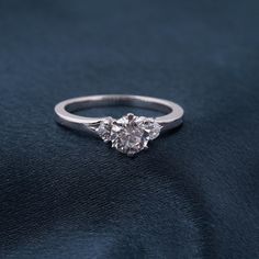 a three stone diamond ring sitting on top of a black cloth