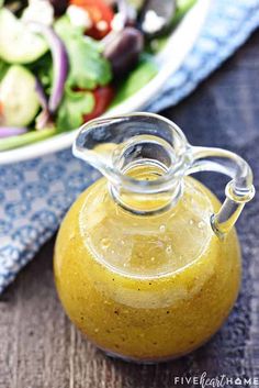 a glass bottle filled with liquid sitting next to a salad