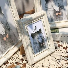 three framed pictures of bears are sitting on a lace doily