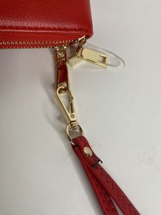 a red handbag with a gold zipper is laying on a white surface next to a pair of scissors