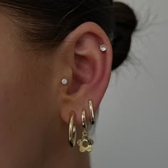 a woman wearing three gold hoop earrings with small diamonds on the top of her ear