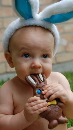 a baby wearing a bunny ears hat eating chocolate