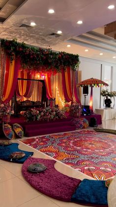 an elaborately decorated room with colorful carpets and flowers on the floor, surrounded by bright colored drapes