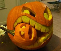 a carved pumpkin with the letter e carved into it's face and mouth, sitting on a table