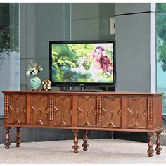 a large wooden entertainment center in front of a flat screen tv on a stand with carved wood legs