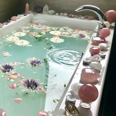 a bathtub filled with water and flowers floating on top of it's sides