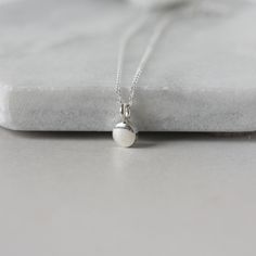 A dainty minimalist accessory that's perfect for everyday wear! This necklace features a tiny sterling silver pebble charm paired with sterling silver cable chain. The small disc is 5mm wide and about 2mm thick and it has a sleek bright polish that gives the necklace a modern feel. The simple design makes this a versatile accessory and it looks chic alone or layered with others. The necklace is fastened with a sterling silver spring ring clasp and you can choose your desired length from the drop Simple Everyday Pendant Charm Necklace, Adjustable Tiny Charm Necklaces For Everyday, Adjustable Minimalist Teardrop Pendant Charm Necklaces, Minimalist Oval Pendant Charm Necklace For Everyday, Minimalist Everyday Charm Necklace With Oval Pendant, Simple Teardrop Pendant Jewelry, Simple Adjustable Charm Necklace For Everyday, Minimalist Tiny Charm Necklaces For Everyday, Silver Minimalist Charm Necklaces For Everyday