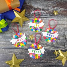 three christmas ornaments with the words love, hope, and peace on them next to presents