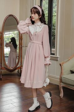 A modern wearable take on french ballroom dresses. Features a high neckline with exquisite ruffles and lace, pearl button up bodice with pintuck details, removable waist belt with belt loops, long blouson sleeves with ruffle cuffs and bows on top, wide pleated swing skirt with a lace chain hem. Concealed side zipper. Lined. S: 13.5" across shoulders, 33" chest, 27" waist, 42" length, 87.5" skirt hemM: 14" across shoulders, 34.5" chest, 28.5" waist, 42" length, 89" skirt hemL: 14.5" across shoulders, 36" chest, 30" waist, 42.5" length, 91" skirt hemXL: 15" across shoulders, 37.5" chest, 31.5" waist, 42.5" length, 93" skirt hem Pink Long Sleeve Dress With Lace Collar, Feminine Ruffled Winter Dresses, Feminine Winter Dresses With Ruffles, Winter Feminine Dresses With Ruffles, Elegant Winter Dresses With Lace Trim, Feminine Long Sleeve Dress With Lace Collar, Elegant Pink Dress With Stand Collar, Elegant Pink Vintage Dress With Ruffles, Pink Feminine Dress With Ruffled Collar