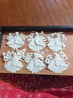 some white paper angel ornaments sitting on a table next to a red and white blanket