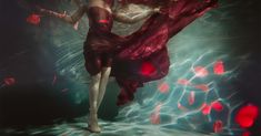 a woman in a red dress standing under water