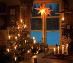 a christmas tree with lit candles in front of a window