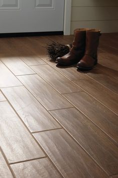 a pair of brown boots sitting on top of a wooden floor next to a door