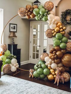 the balloon arch is decorated with giraffes, leopard print and green balloons