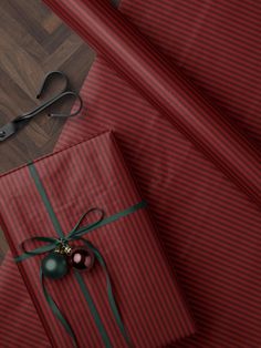 two wrapped presents sitting on top of a wooden floor next to a pair of scissors