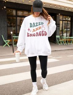 a woman wearing a white sweatshirt and black leggings is crossing the street in front of a building