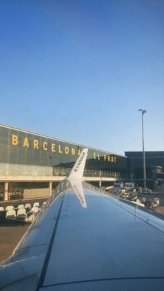 the wing of an airplane as it flies by in front of a barcelon airport