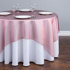 the table is set with white plates and silverware, along with pink napkins