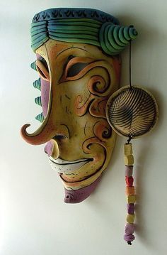 a colorful mask hanging on the wall next to a beaded ball and key holder