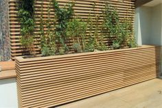 a wooden planter filled with lots of plants on top of a wall next to a building