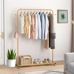 a rack with clothes hanging on it next to a chair and potted plant in a living room