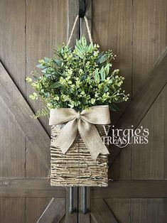 a basket hanging from the side of a wooden door with a bow tied around it