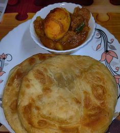 there is a plate with some food on it and a bowl of stew in the background