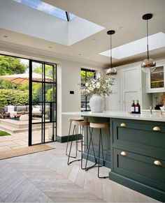 a kitchen with an island and bar stools next to the glass door leading outside