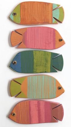 three fish are painted on wood with different colors and sizes, one is orange, the other is blue