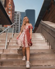 a woman is standing on some steps in a dress