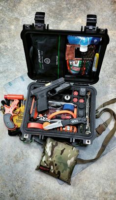 an open tool bag filled with tools on top of a cement floor next to other items