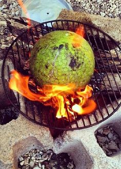 a green ball sitting on top of an open grill with flames coming out of it