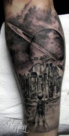 a man's leg with a black and grey tattoo on it, featuring an image of saturn