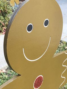 a close up of a wooden sign with a face and hands painted on it's side