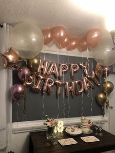 a birthday party with balloons, cake and confetti on a table in front of a chalkboard